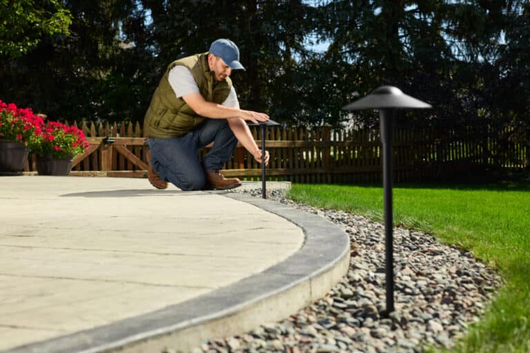 Worker installing landscaping light lamp